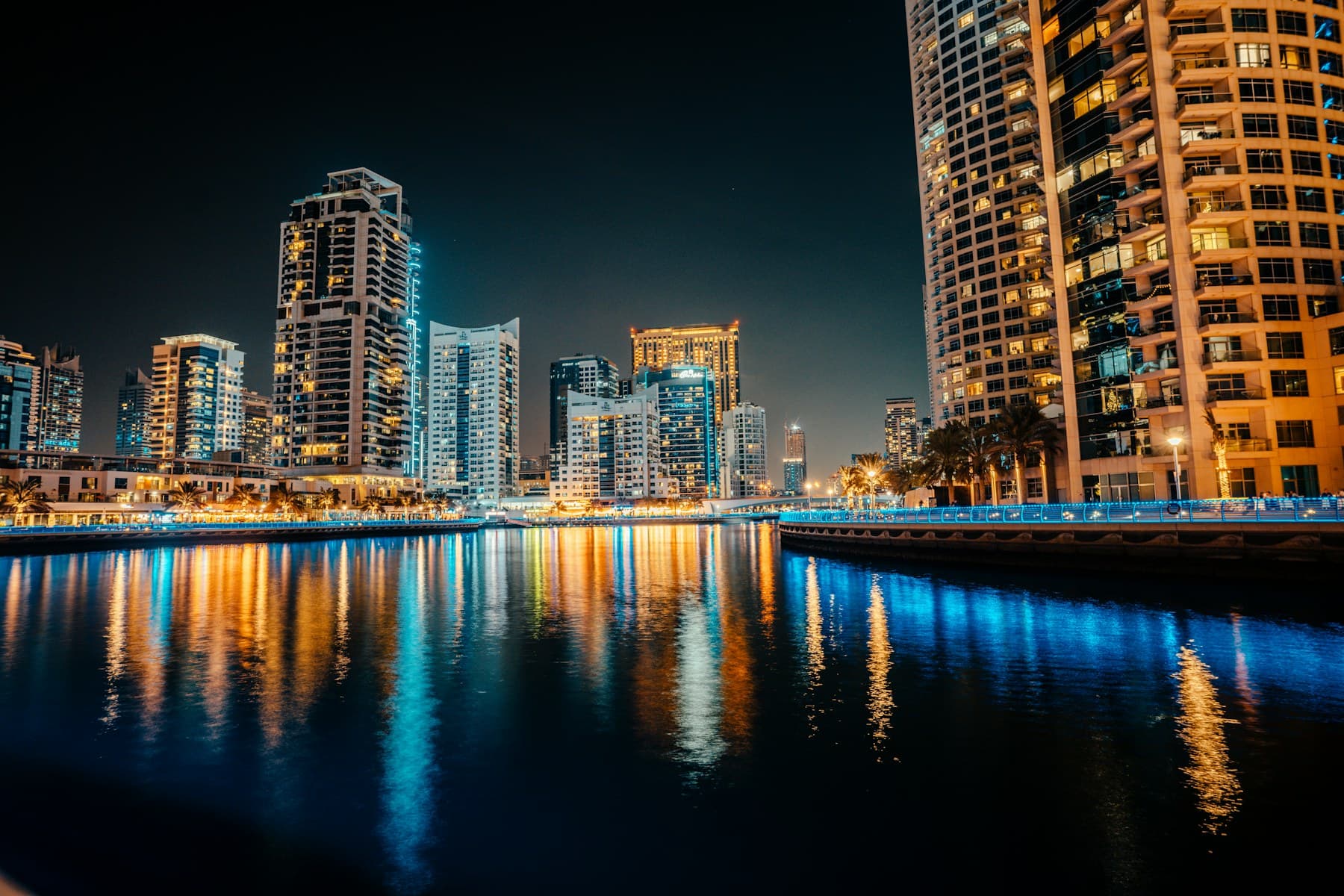 Dubai Marina waterfront at night with tower lights reflected in the water